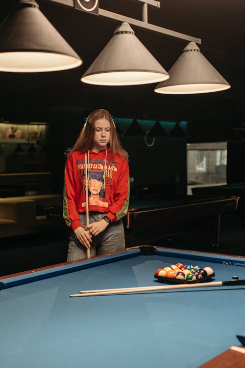 A Woman Holding Cue Stick while Looking at Billiard Balls