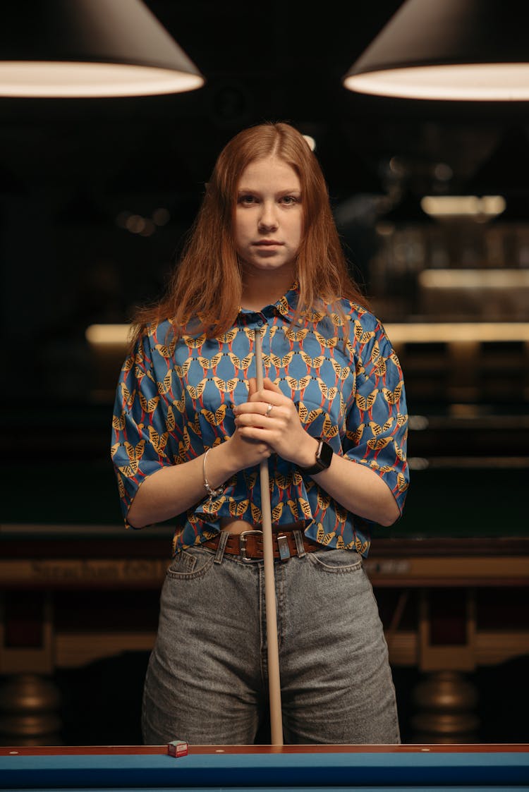 Redhead Woman Standing An Holding A Pool Stick 