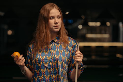 A Woman Holding a Cue Stick and a Billiard Ball