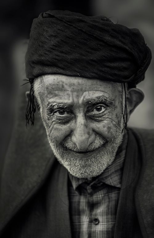 Free Portrait of a smiling elderly man wearing a turban in Uraman Takht, Iran, captured in grayscale. Stock Photo