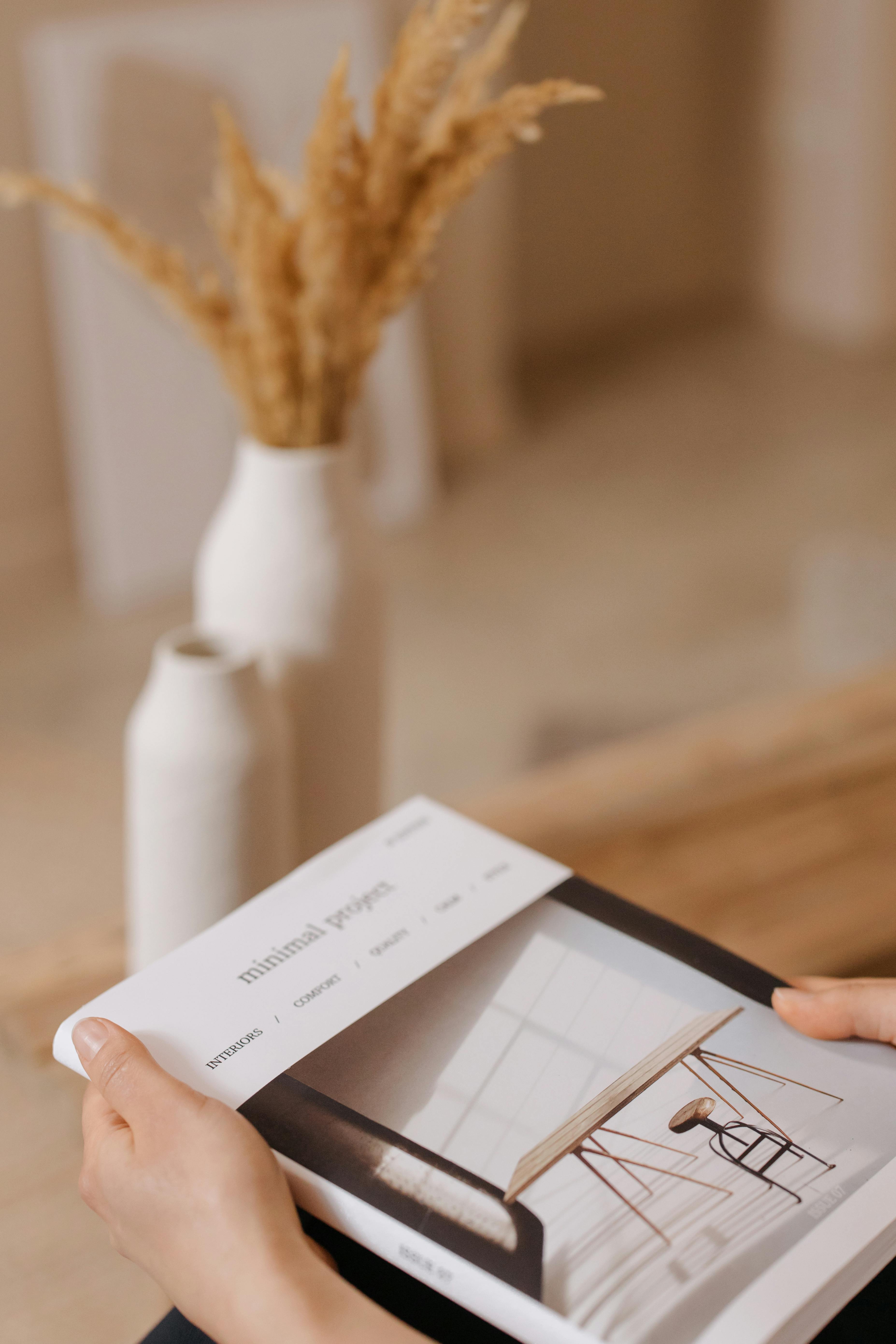 Hands holding a minimalist magazine showcasing modern interior design.