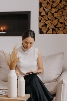 Woman reading a book in a minimalist Scandinavian living room, creating a cozy vibe.