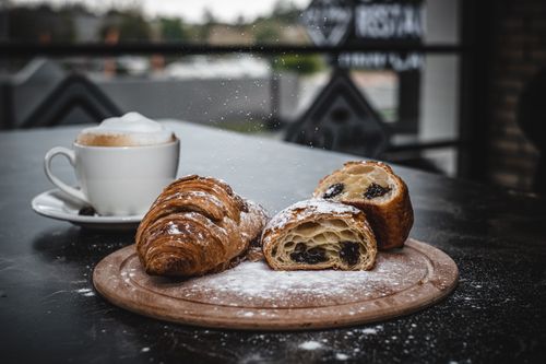 Free Delight in a croissant and cappuccino dusted with powdered sugar on a cozy terrace. Stock Photo