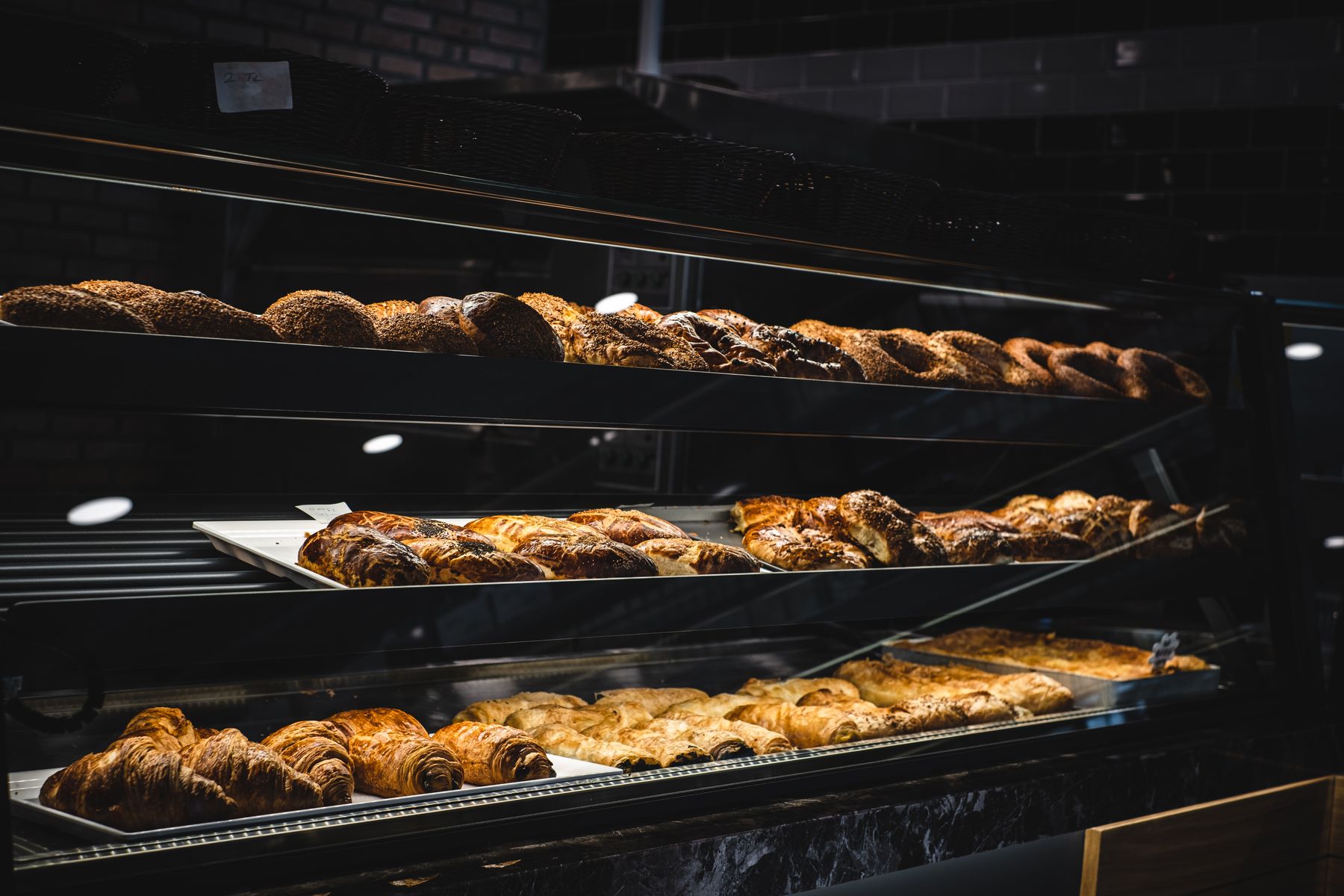 A glass counter at Riverbend Bakery filled with fresh loaves, pastries, and rolls.