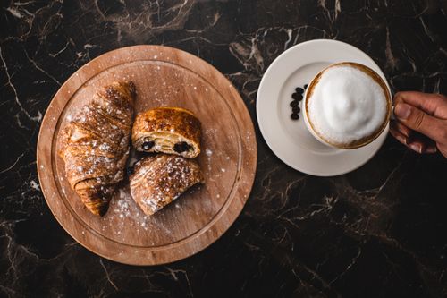 Free Delightful breakfast of croissants and cappuccino on a marble table, perfect for a cozy meal Stock Photo