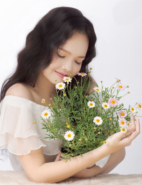 Free Ethnic woman closing eyes with blossoming flowers of chamomiles in hands in studio Stock Photo