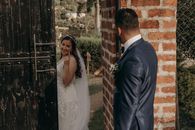 Cheerful ethnic woman in white dress showing up with finger against anonymous stylish male partner on wedding day