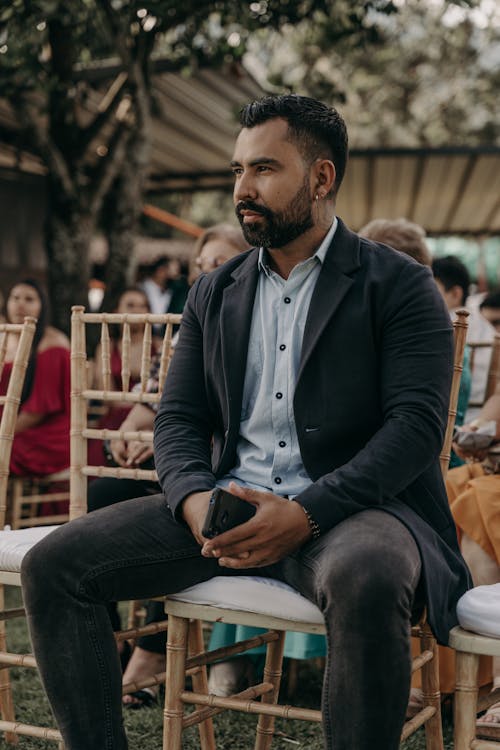 Free A Bearded Man Sitting on a Chair during an Outdoor Ceremony Stock Photo