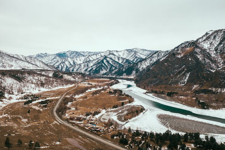 Drone Shot Of A River And Mountains Covered In Snow