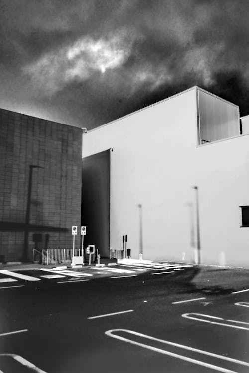 Grayscale Photography of Buildings Near Parking Lot