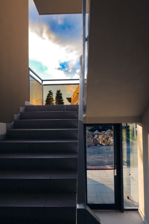 Free Minimalist staircase with glass railings offering a view of the sky and outdoors, capturing sunset tones. Stock Photo