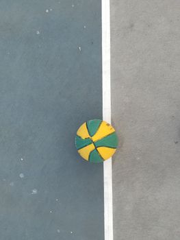 A vibrant basketball on a concrete court with a dividing line in Varna, Bulgaria.