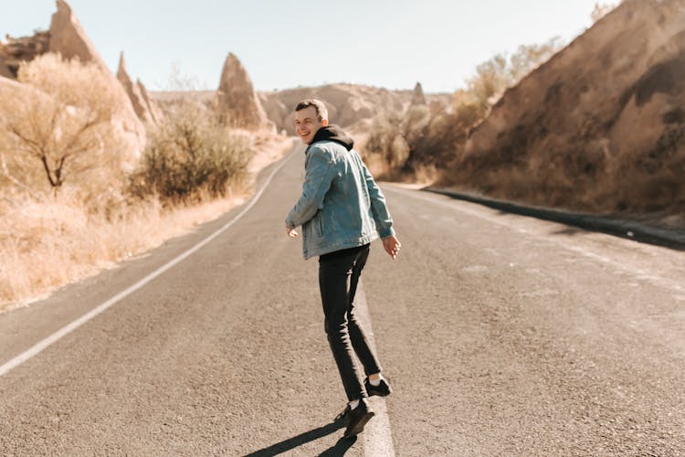 A Smiling Young Man In The Middle Of A Road  