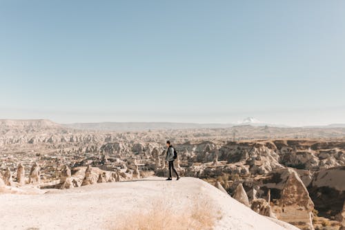 A Man Standing on a Hill Looking at Rock Formations in Cappadocia 