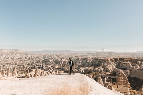 Free A lone traveler stands on a hill in Cappadocia, Turkey, enjoying the breathtaking rock formations and expansive views. Stock Photo