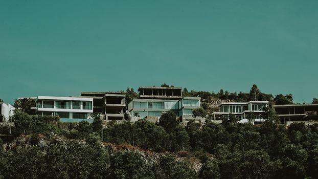 Contemporary hillside villas surrounded by lush greenery under an expansive sky.