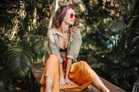 Woman in Gray Jacket and Orange Skirt Sitting on Brown Wooden Bench