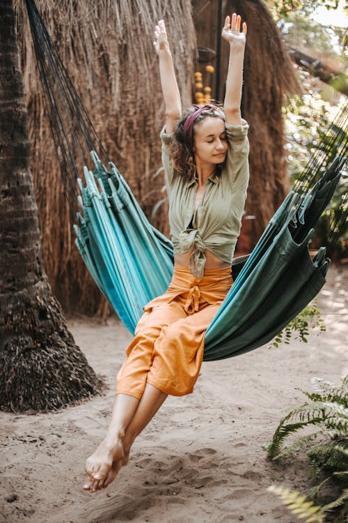 A Woman Sitting on a Hammock and Stretching