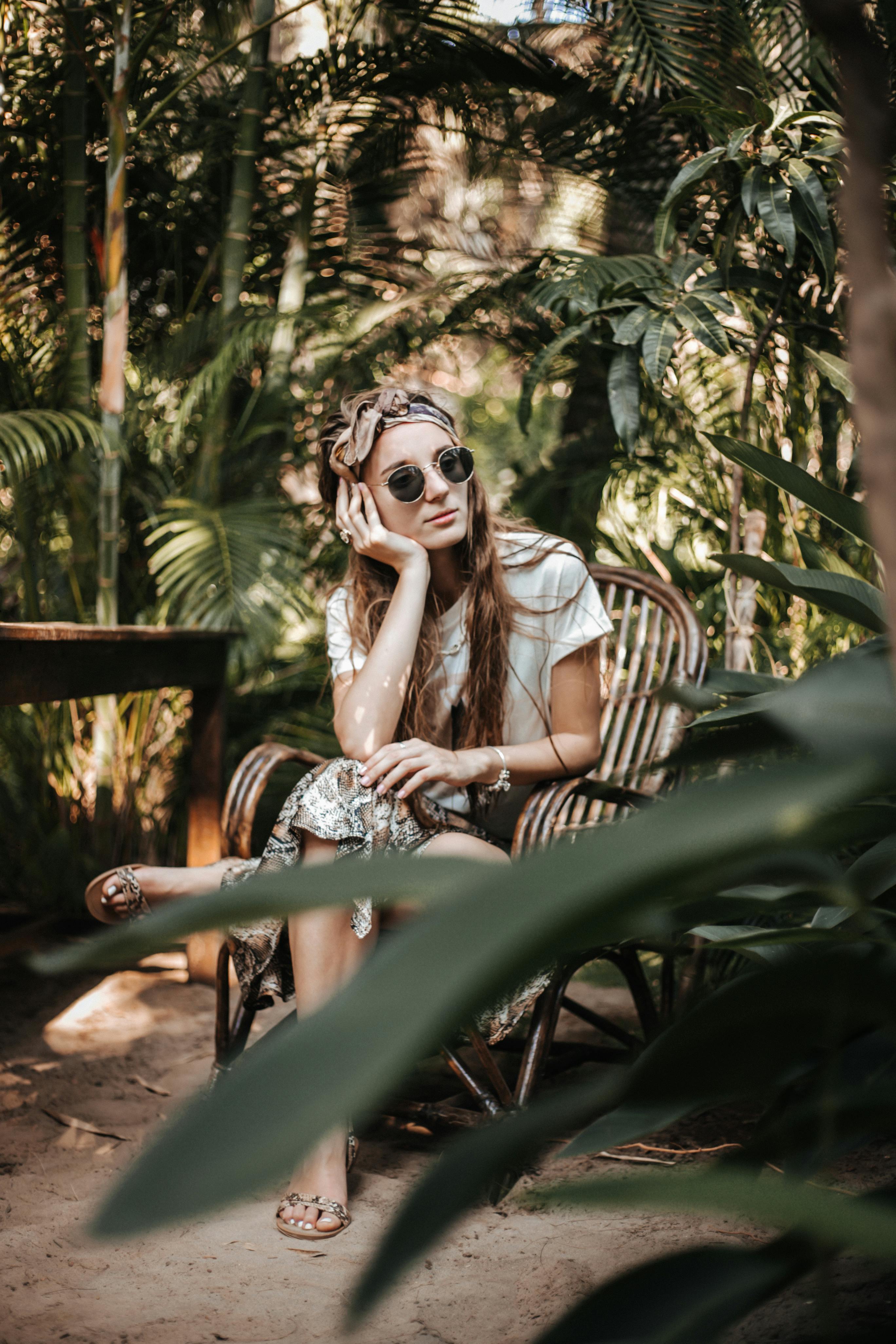 woman resting chin on hand sitting on a wooden armchair