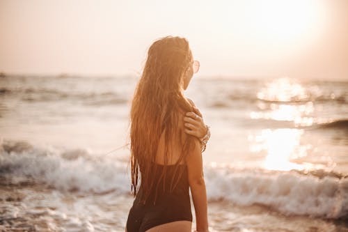 A Woman in Swimsuit at the Beach During Sunset