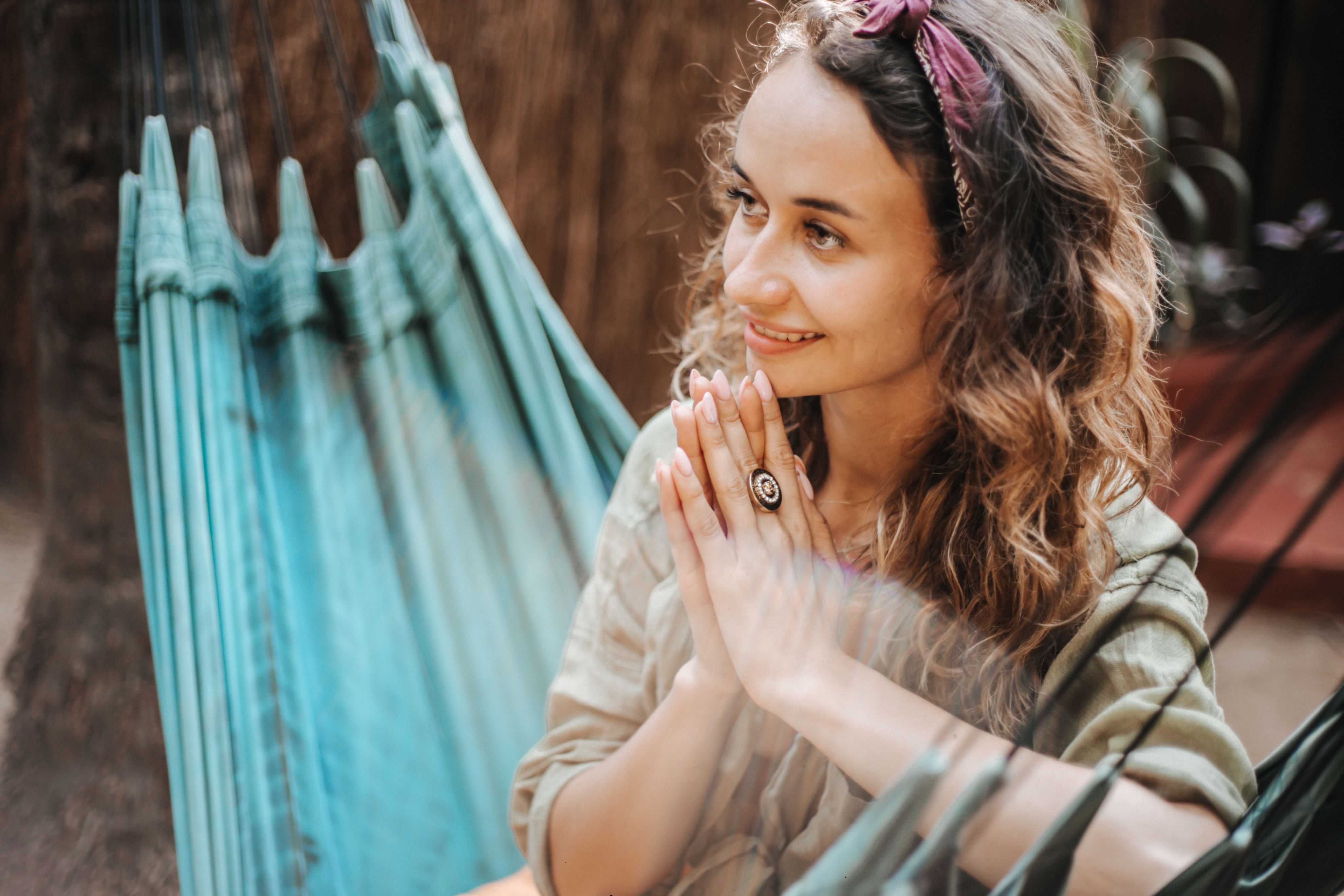 A woman relaxing in a hammock, enjoying leisure time and smiling outdoors.