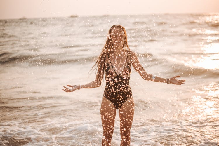 A Woman In A Swimsuit Splashing Seawater