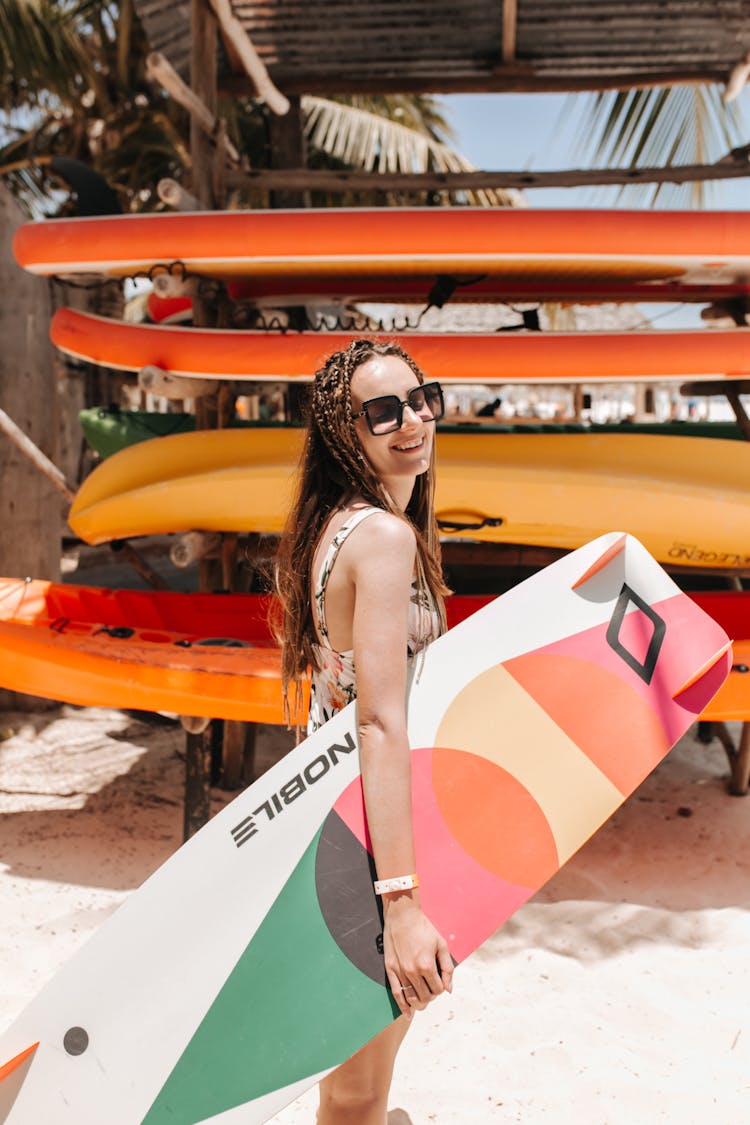 Woman In Black Sunglasses Carrying A Surfboard