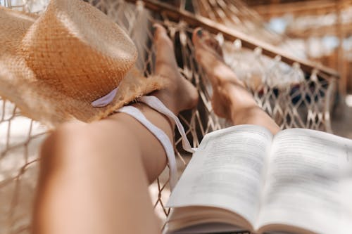 Free A Book and a Straw Hat on a Woman's Legs  Stock Photo