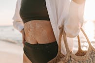 一个穿着泳衣的女人在沙滩上穿着编织袋的特写，享受夏日的阳光