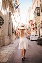 Woman in White Dress Walking on Sidewalk