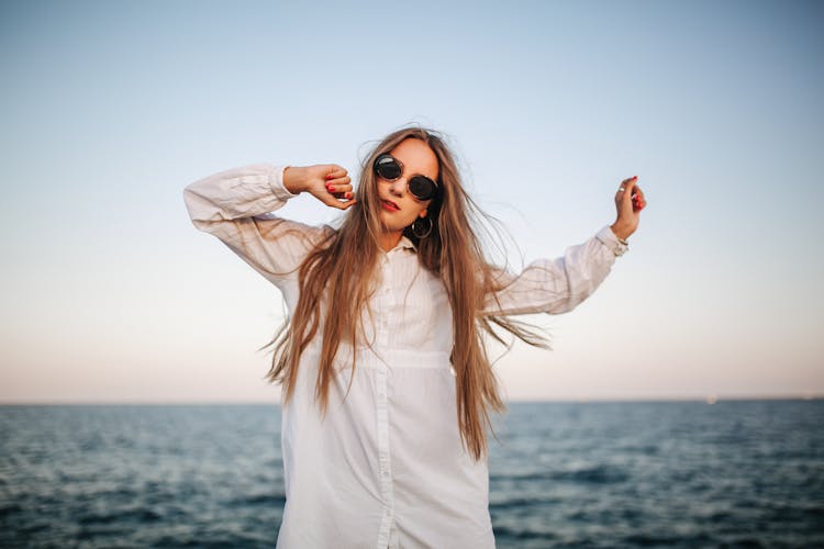 Pretty Woman In White Long Sleeve Dress Wearing Sunglasses On The Beach