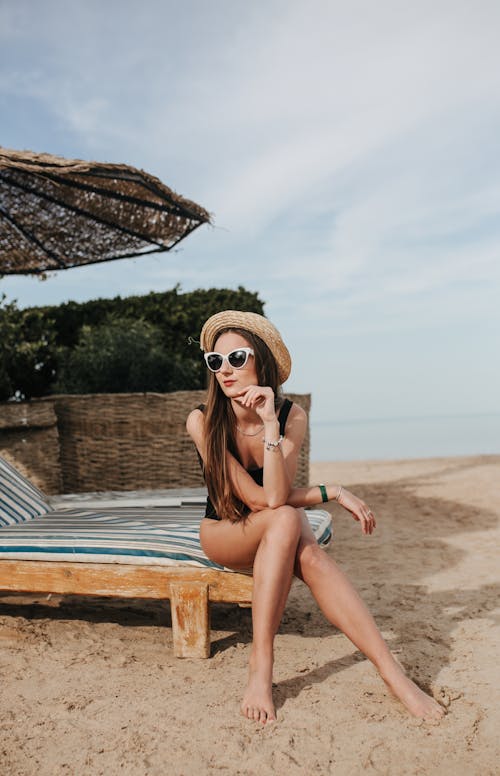 A Woman in Black Swimsuit Sitting on a Sun Lounger on the Beach