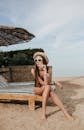 Woman in Black Bikini Sitting on Brown Wooden Bench