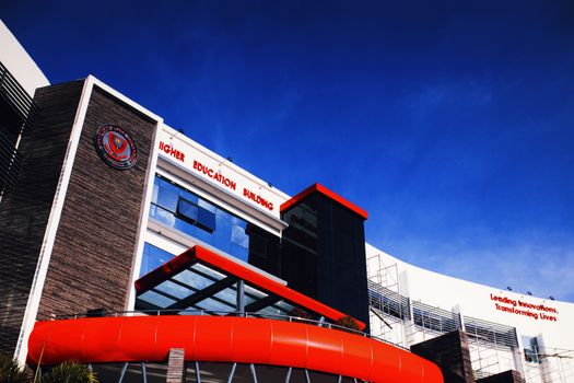 Low angle shot of a modern university building facade under a clear blue sky.