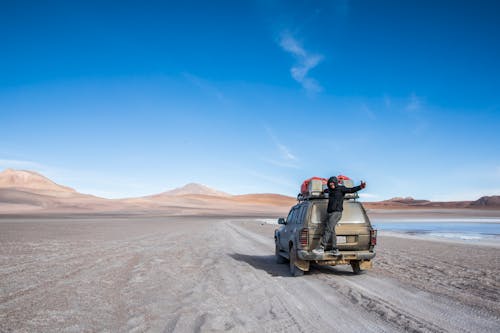 Man Standing on Trunk of SUV on Desert