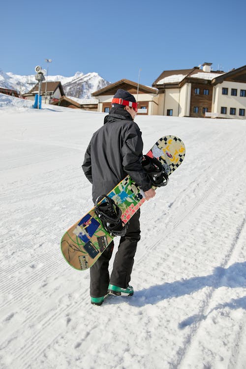 Person in Black Jacket and Pants Holding His Snowboard