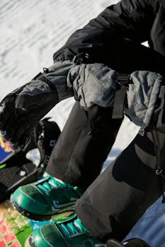 Snowboarder adjusting gloves, getting ready for a winter slope ride.