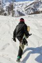 Person in Black Jacket and Green Pants Walking on Snow Covered Ground