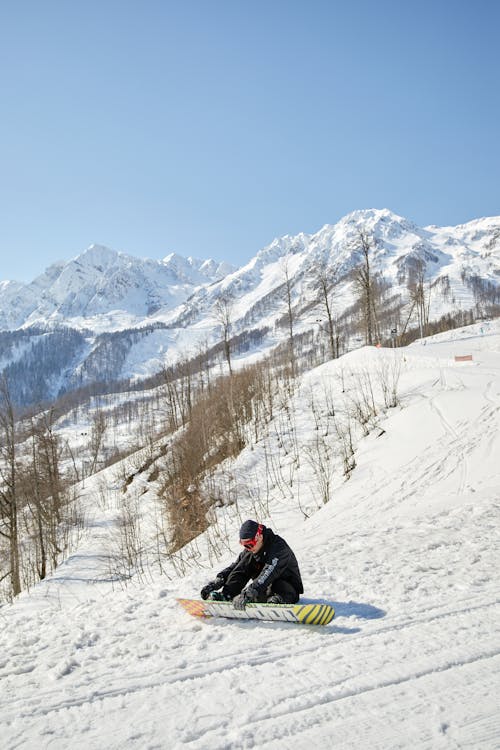 A Snowboarder Putting On his Snowboard
