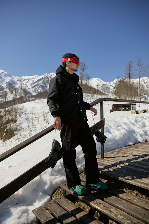 Man Standing on Wooden Steps in Snowy Mountain Scenery