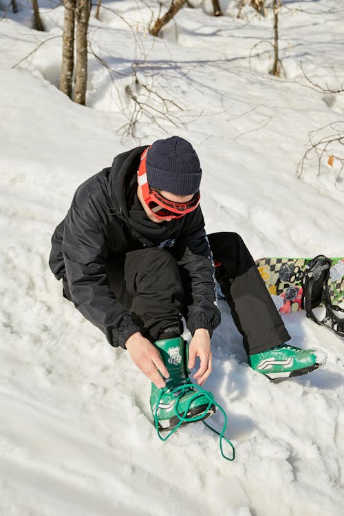 A Snowboarder Tying His Shoes