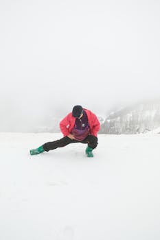 Person stretching in a snowy winter landscape, wearing bright winter clothing. Ideal for fitness themes.