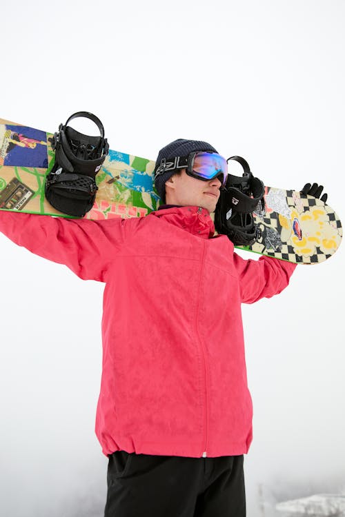 A Man in Winter Clothing Carrying a Snowboard