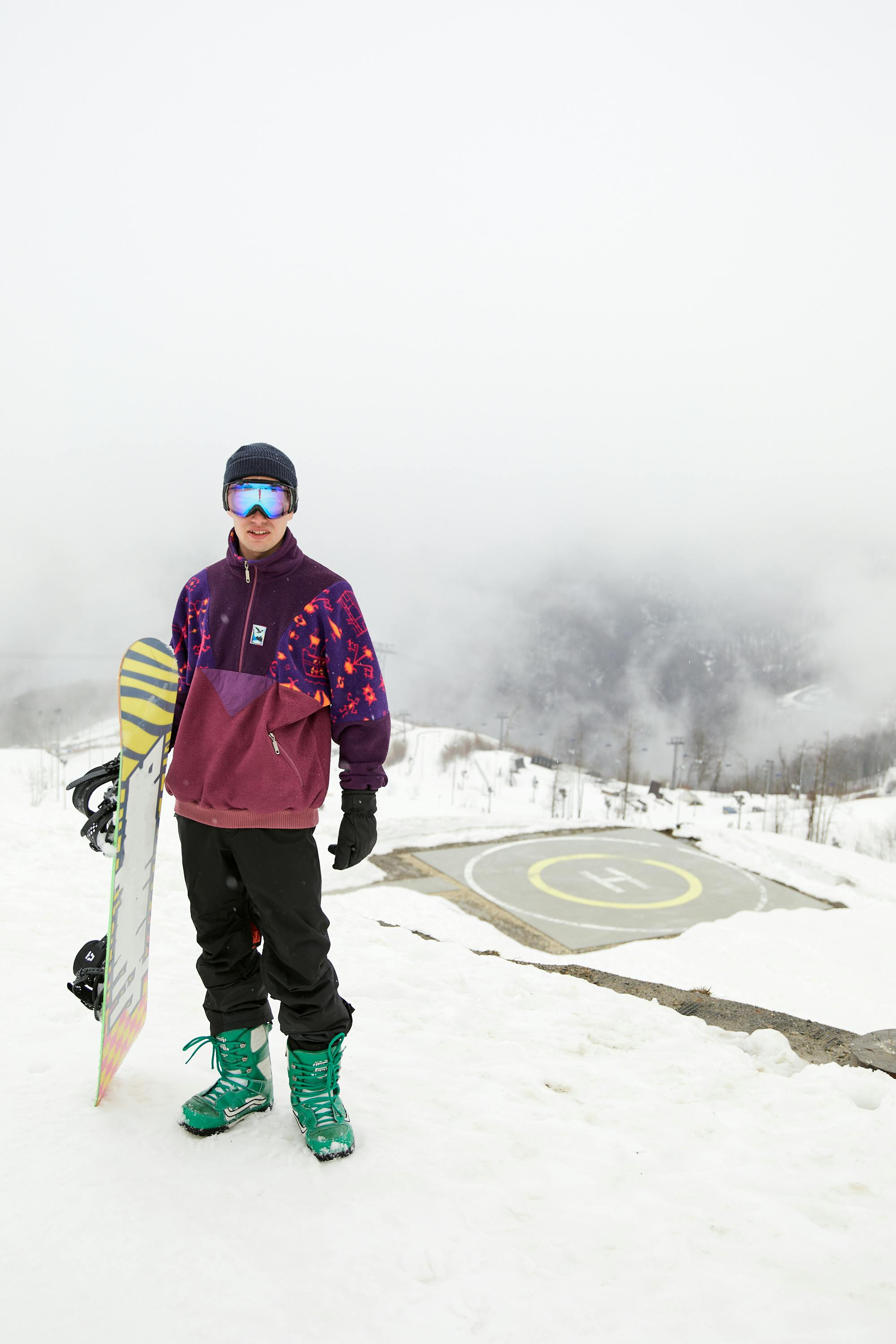 a man in winter clothing carrying a snowboard