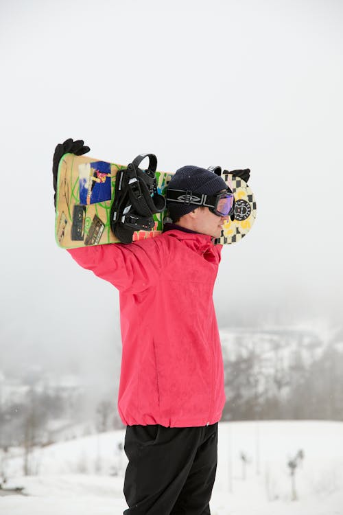 A Man in Winter Clothing Carrying a Snowboard