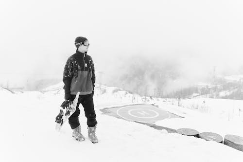 A Man in Winter Clothing Carrying a Snowboard