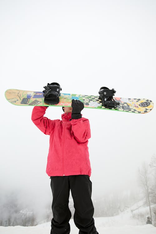 A Man in Winter Clothing Holding a Snowboard