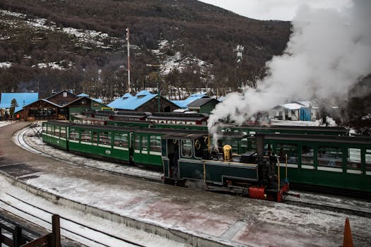 A steam train at Ushuaia station in winter, showcasing snowy landscapes and vintage transportation.
