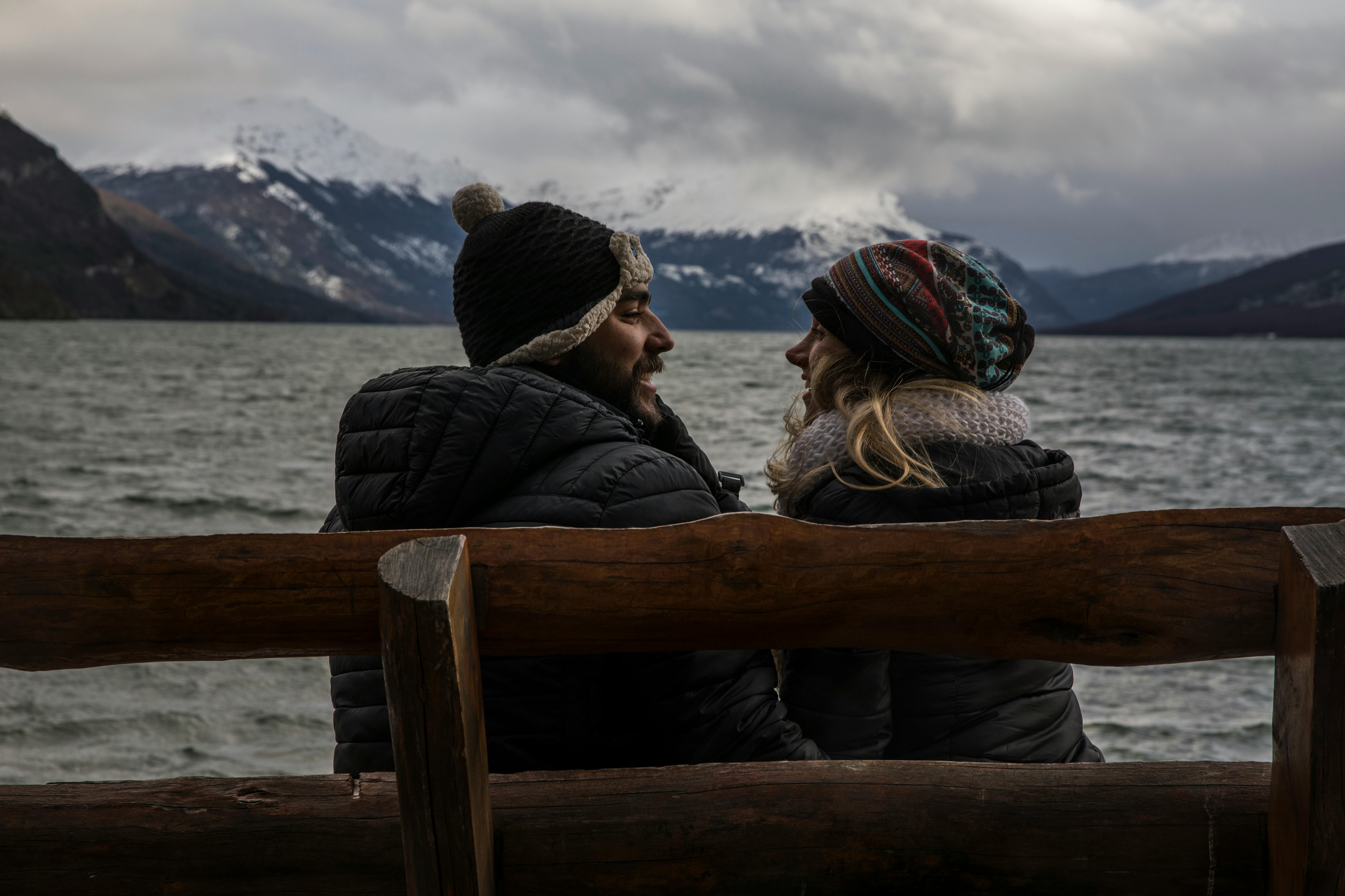 Casal em banco de madeira à beira do lago em Tierra del Fuego, Patagônia, para uma escapada romântica luxuosa.