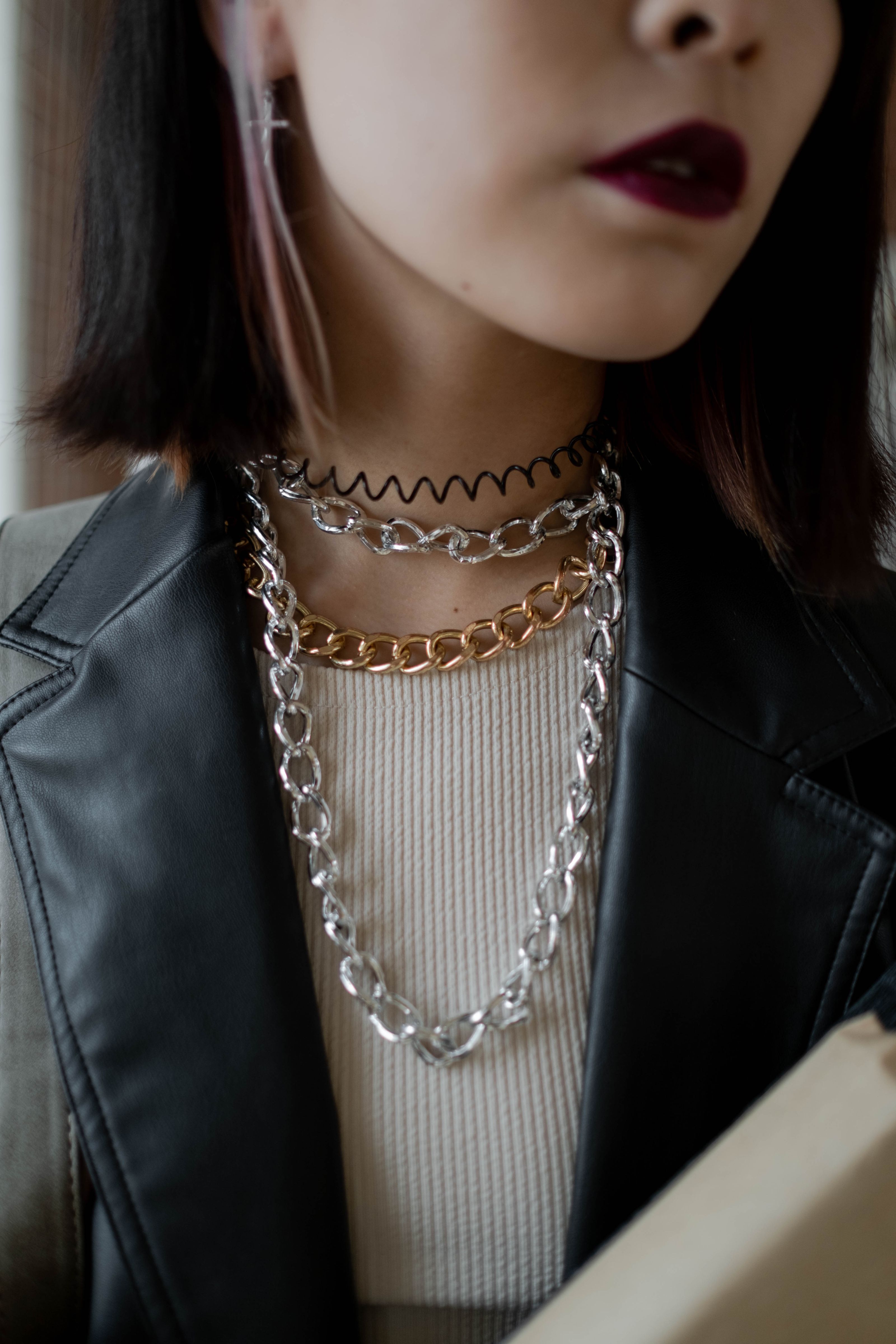 Close-up de moda chique com colares de corrente diversos e batom ousado, perfeito para inspiração de estilo.